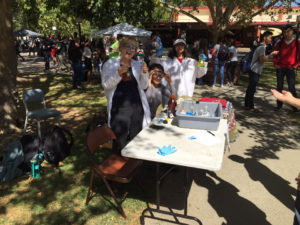 three people standing at table with chemistry demonstrations